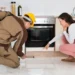 Top 5 House Bugs to Look Out for in Western Washington - pest control technician inspecting under stove with female homeowner