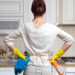 Why Ants Persist in a clean home: 5 Reasons. A woman stands in a kitchen ready to deep clean with cleaning supplies.